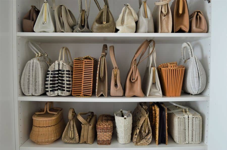 Shelf filled with various woven and leather handbags in neutral tones, neatly organized by size and style