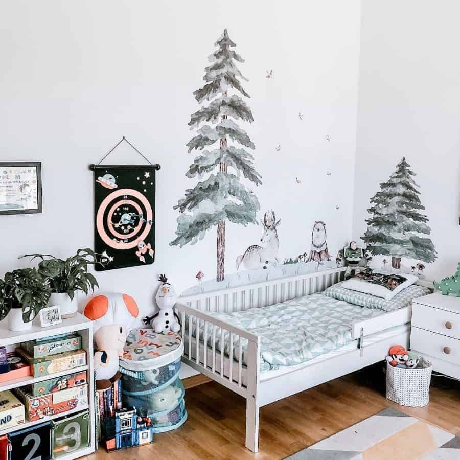 Nature-inspired kids' room with a forest mural, white wooden bed, playful stuffed toys, and cozy storage for books and games