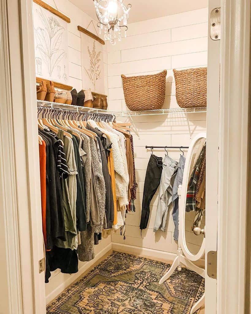 A small walk-in closet with hanging clothes, woven baskets on shelves, and a standing mirror. A decorative rug covers the floor