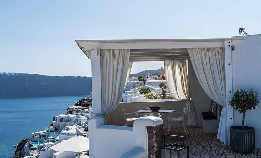 Elegant poolside cabana with flowing white curtains, cozy seating, and stunning ocean views, creating a serene outdoor retreat