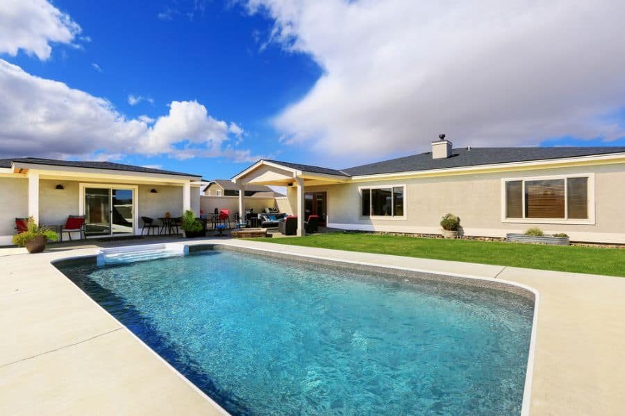 Modern backyard with a sparkling pool, a cozy covered patio, and a stylish pool house, offering a perfect outdoor relaxation space