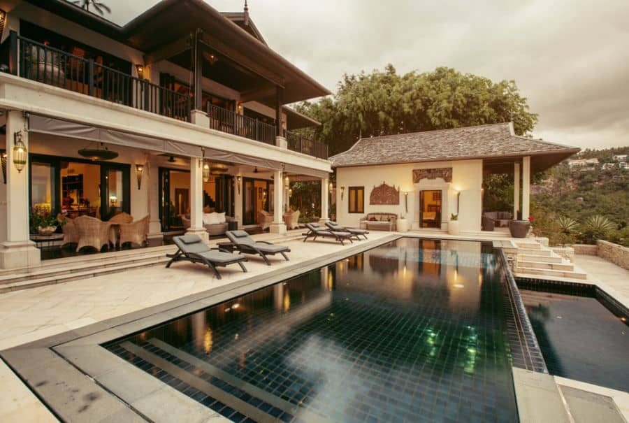 Luxurious villa with an elegant pool house, black-tiled infinity pool, and stylish outdoor seating, offering a serene and tropical retreat