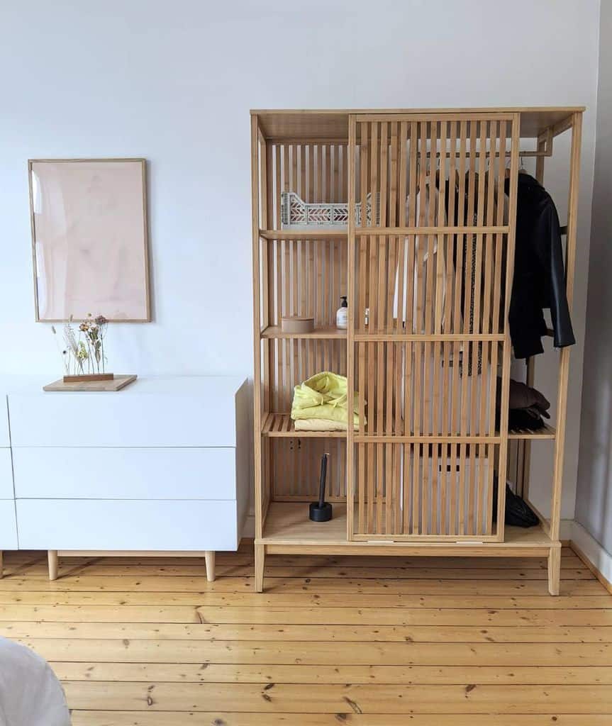 Minimalist wooden slatted wardrobe with open shelving and hanging space, neatly organizing clothes, storage boxes, and decor items