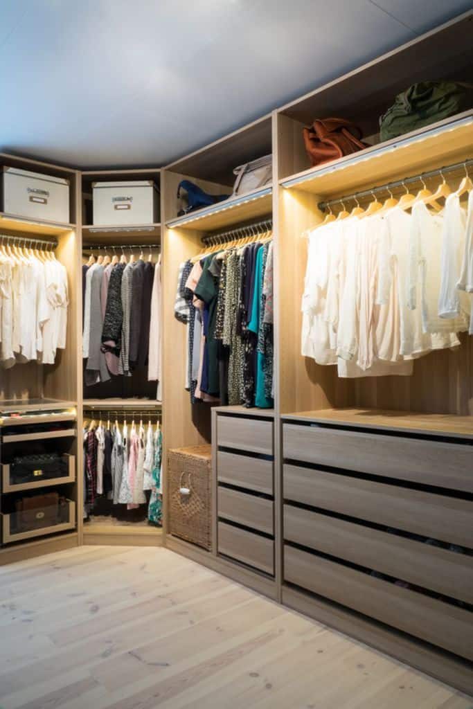 A well-organized wooden wardrobe with clothes hanging, drawers, and shelves holding boxes and bags