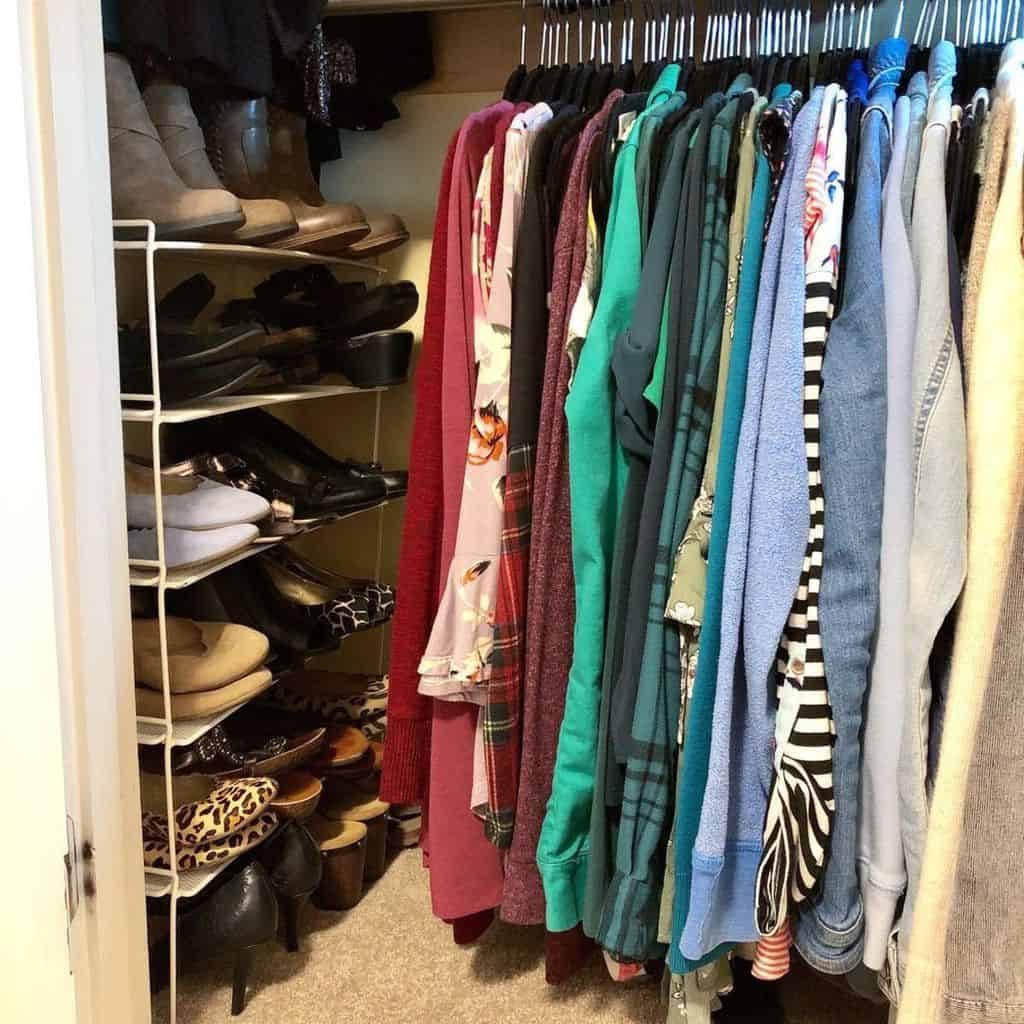 A closet with neatly hung clothes in various colors and patterns on the right, and shoe racks with assorted footwear on the left