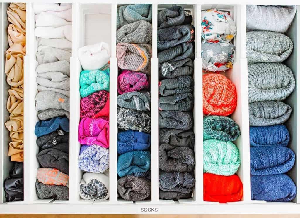 A neatly organized drawer with socks in various colors and patterns, separated into compartments