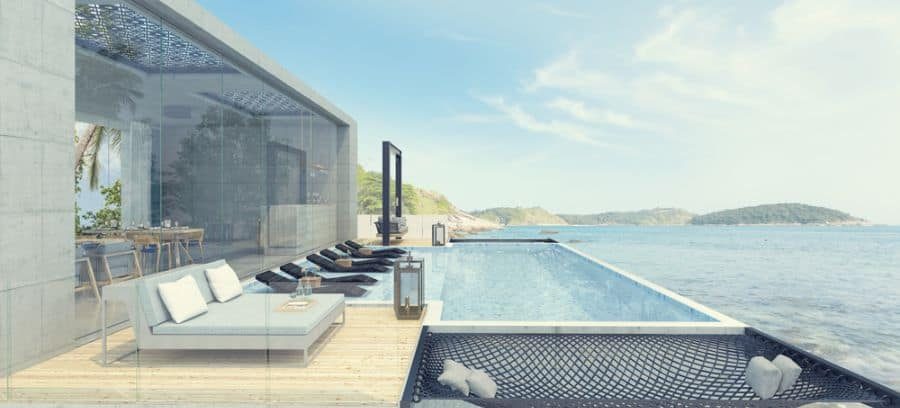 Luxury glass pool house with an infinity pool overlooking the ocean, stylish lounge seating, and an open-concept design for a serene retreat