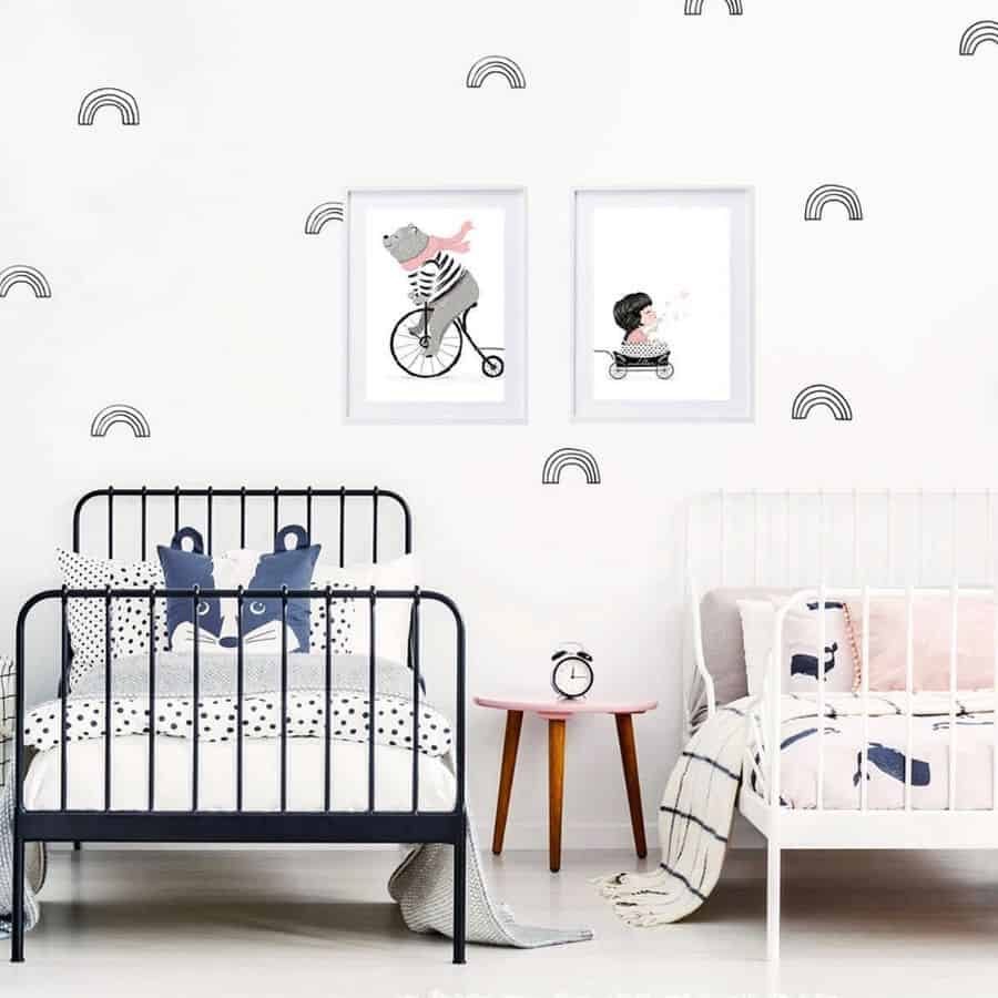 Modern kids' bedroom with matching black and white metal beds, playful wall art, rainbow decals, and cozy monochrome bedding