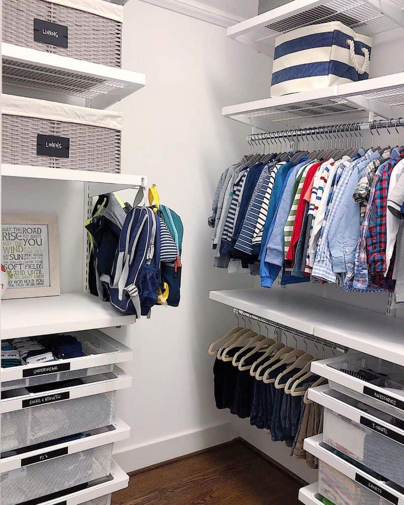 Organized closet with clothes on hangers, labeled storage bins, and folded items on shelves containing shirts, pants, and various accessories