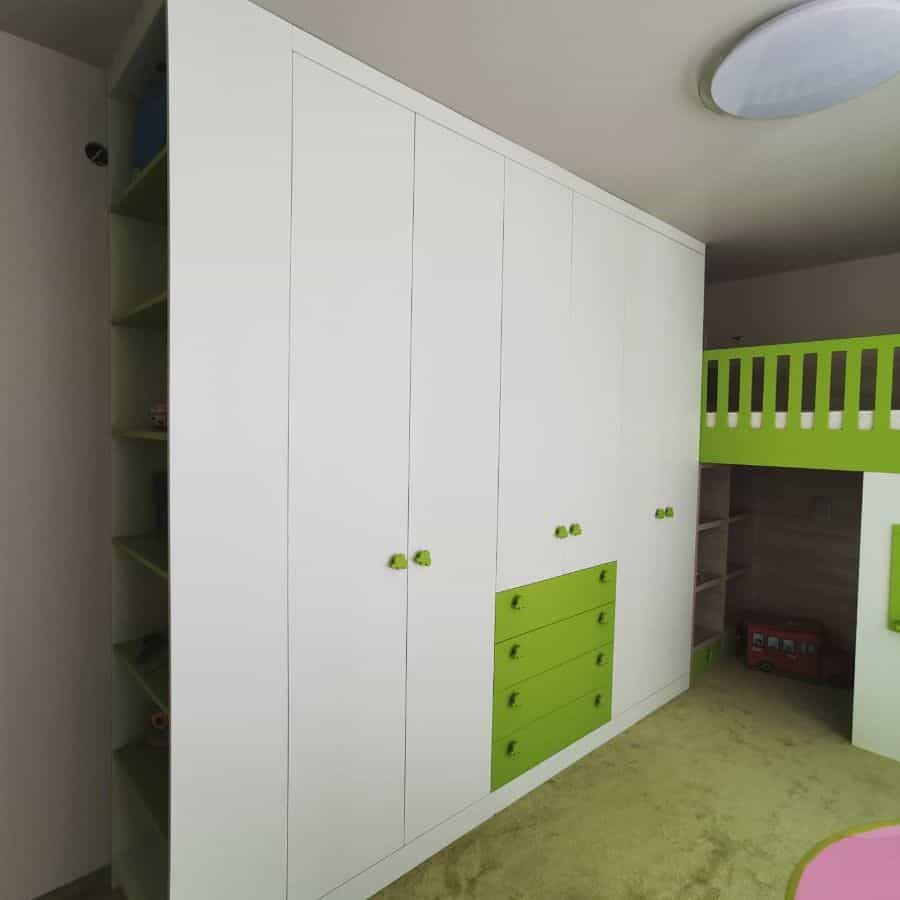 Modern kids' room with a large white and green built-in wardrobe, loft bed, and open shelving for organized storage