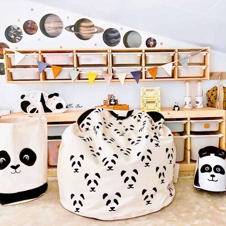 Playful kids' room with panda-themed bean bag chairs, wooden storage shelves, space-themed wall decals, and colorful pennant bunting