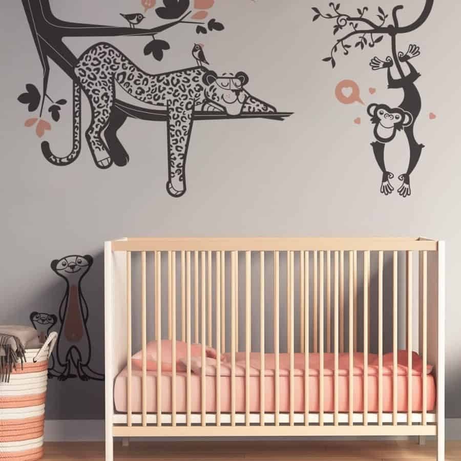 Nursery with a minimalist wooden crib and jungle-themed wall decals featuring a lounging leopard, playful monkeys, and cheerful meerkats on a soft-toned background