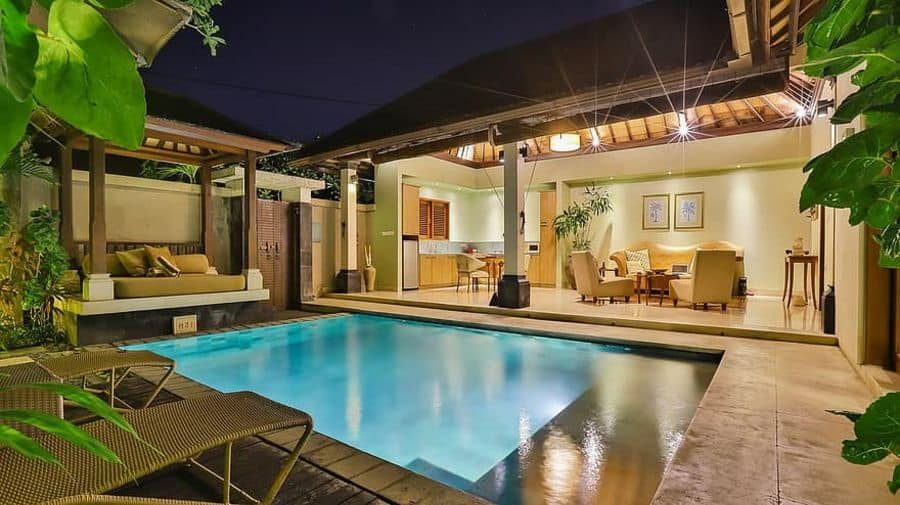 Elegant tropical pool house with an open-concept design, warm lighting, a private pool, and a cozy outdoor lounge area for relaxation