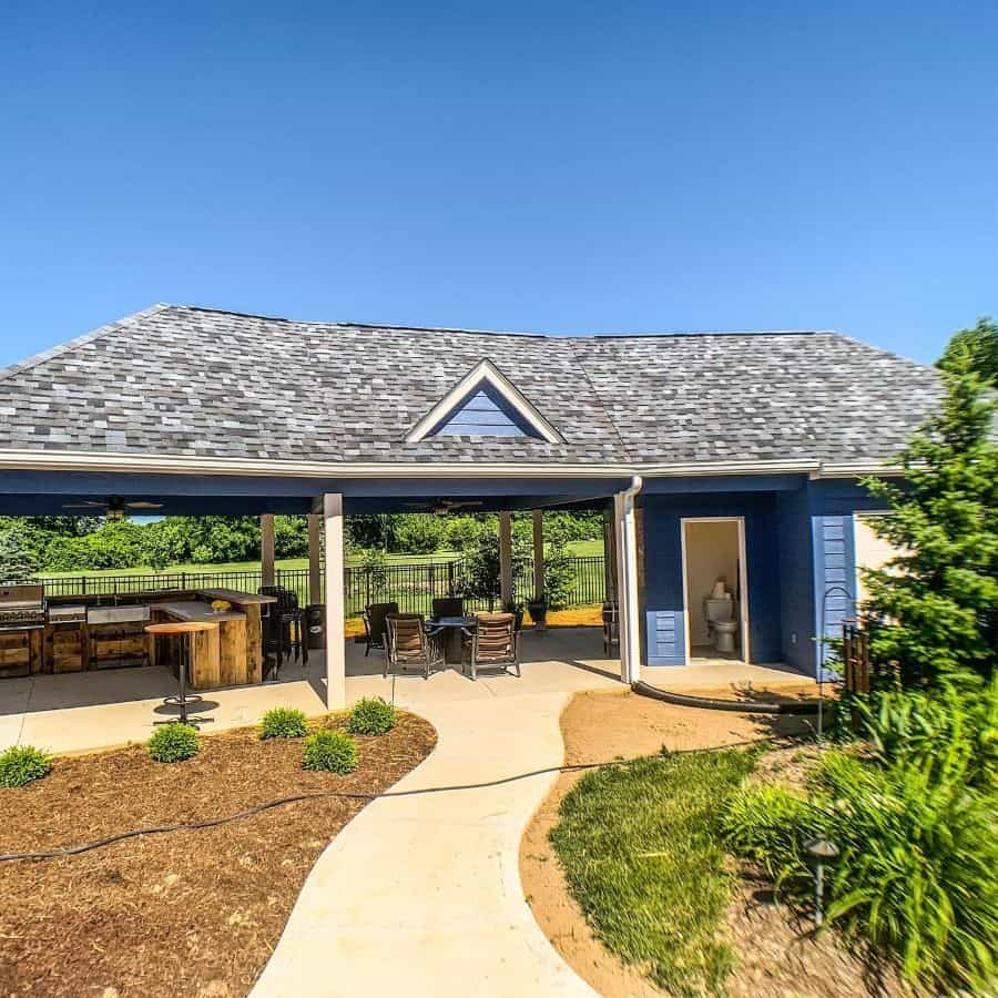 Spacious pool house with a covered outdoor kitchen, dining area, and a restroom, offering a stylish and functional backyard retreat