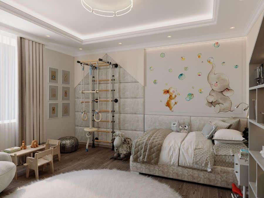 Modern kids' bedroom with a neutral color scheme, featuring a soft upholstered bed, a climbing wall with gym rings, a play area with a small wooden table and chairs, and a whimsical elephant and rabbit wall mural with floating bubbles