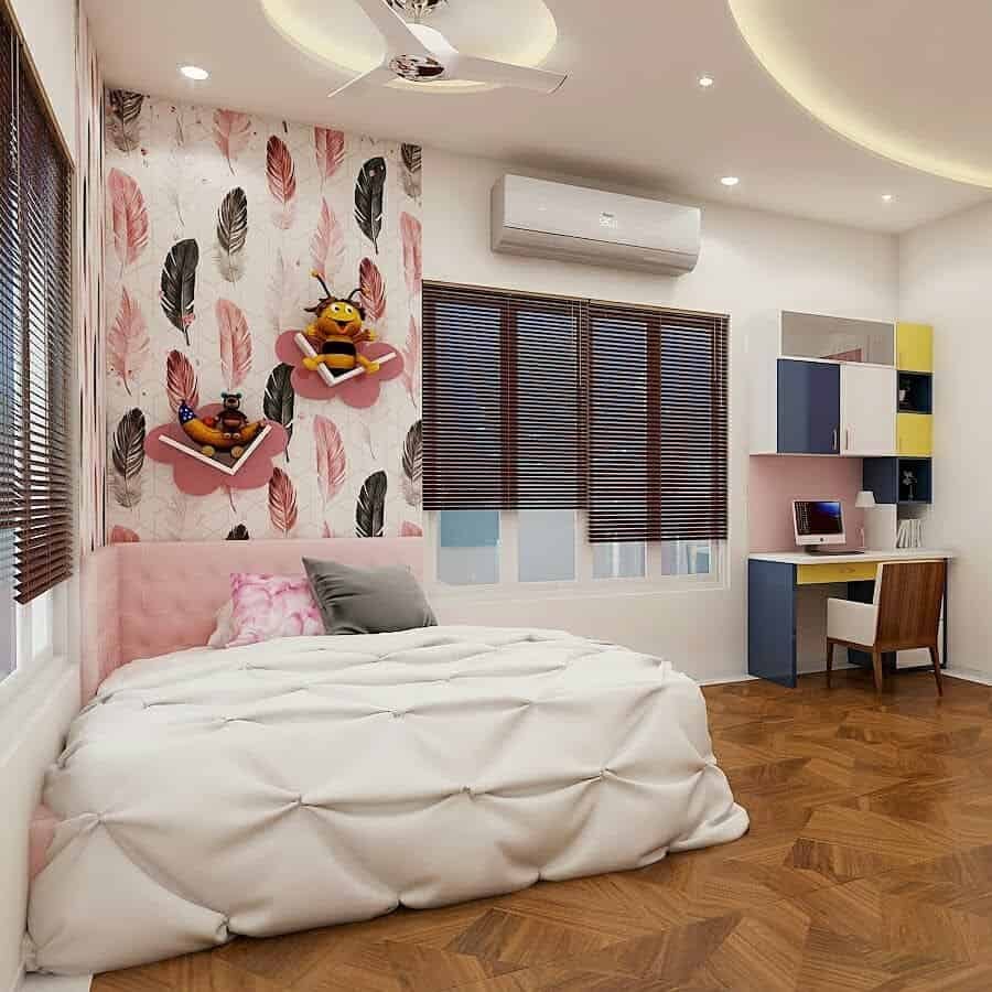 Modern kids' bedroom with a soft pink and white color palette, featuring a tufted bed, feather-patterned wallpaper, floating cloud-shaped bookshelves with stuffed toys, a study desk with colorful cabinets, and wooden flooring