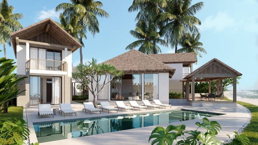 Luxury beachfront villa with a modern pool house, thatched roofs, and sun loungers, surrounded by palm trees for a tropical retreat