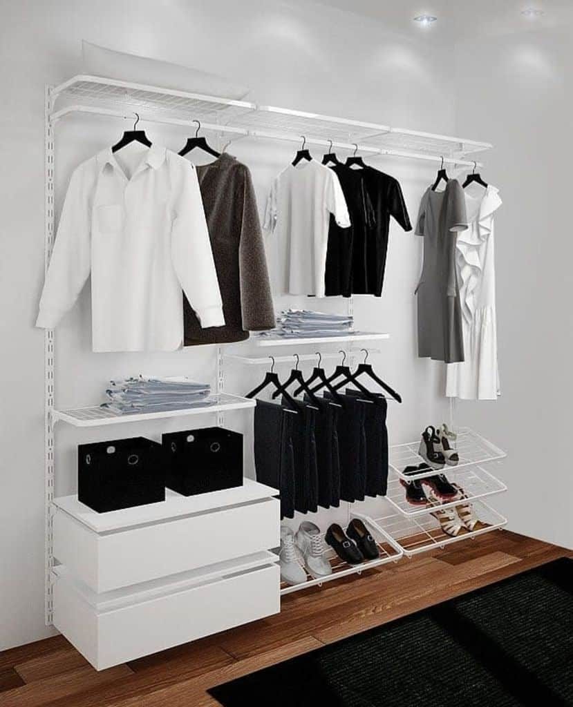 Minimalist closet with neatly hung clothes, folded items, shoes, and storage boxes in bright white shelving and wooden floor