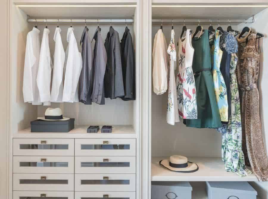 Organized closet with white shirts and dark jackets on the left, colorful dresses on the right, and hats on the shelves below