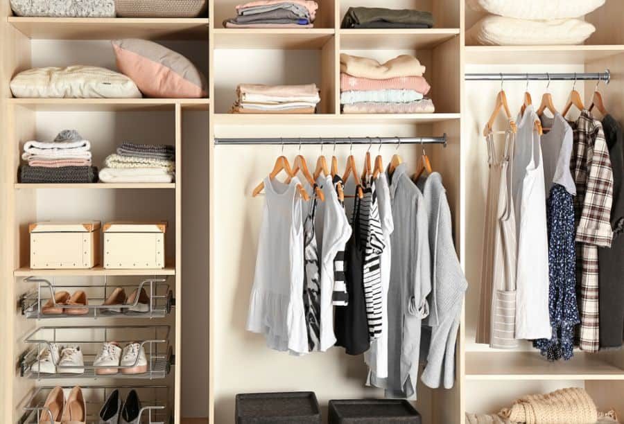 Organized closet with folded clothes, hanging garments, shoes, and storage boxes on shelves and racks