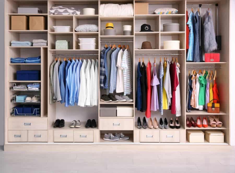 Organized wardrobe with clothes hanging, folded items, hats, shoes, and boxes on shelves and in drawers