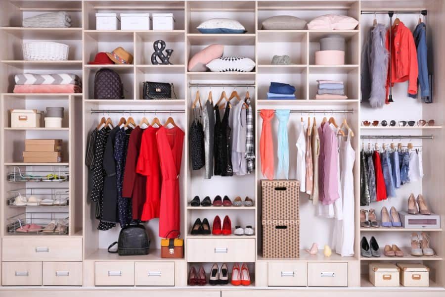 Organized wardrobe with clothes, handbags, shoes, and storage boxes; various clothing items hang neatly on wooden hangers