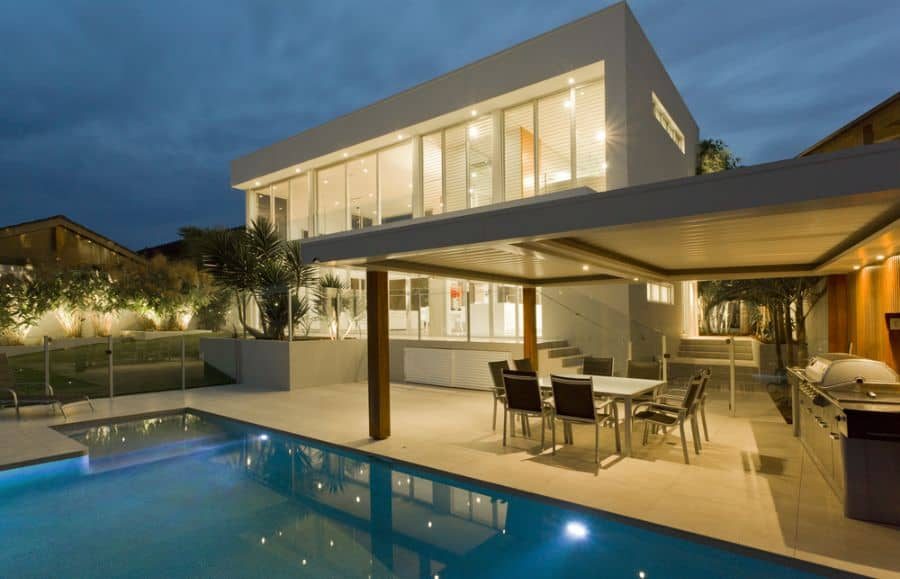 Modern poolside outdoor kitchen with a sleek pergola, dining area, and built-in grill, offering a stylish and functional entertainment space