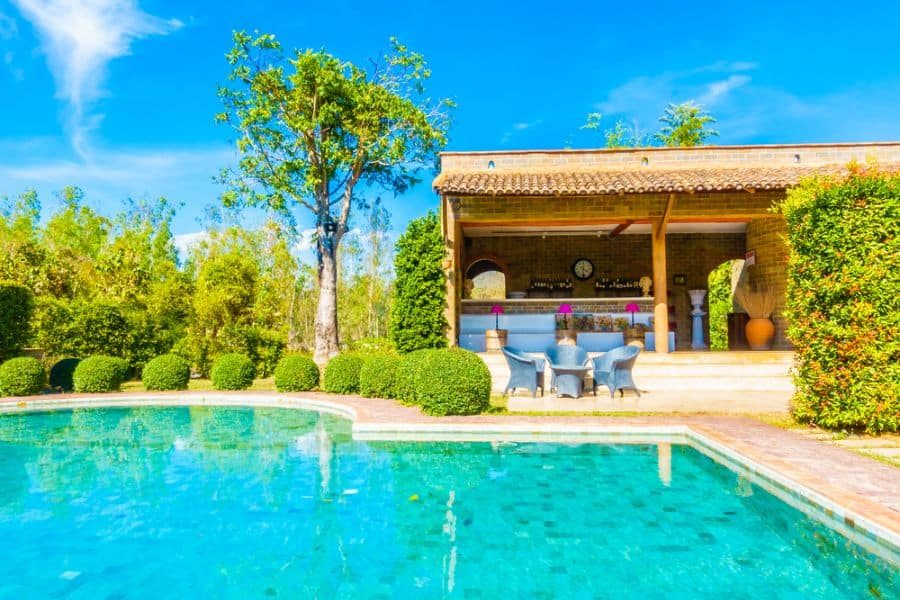 Charming outdoor poolside bar with rustic wooden accents, cozy seating, and lush greenery, creating a relaxing and inviting retreat