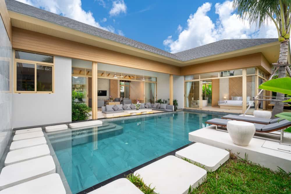 Luxurious modern pool villa with an open-concept design, stylish lounge seating, and a serene private pool surrounded by tropical greenery