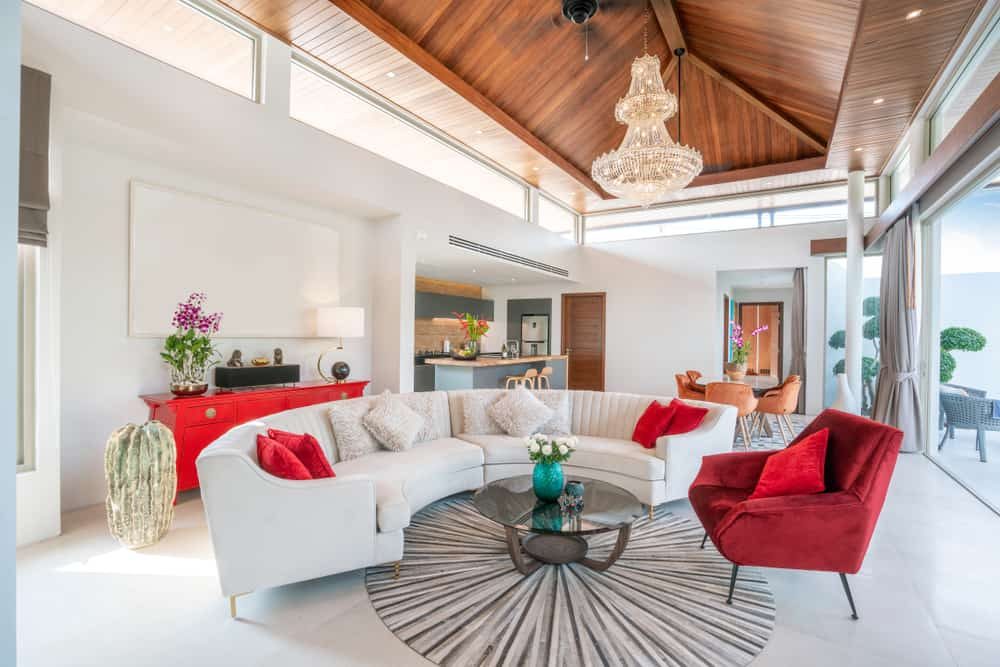 Elegant pool villa interior with a vaulted wooden ceiling, crystal chandelier, stylish modern furniture, and an open-concept living space