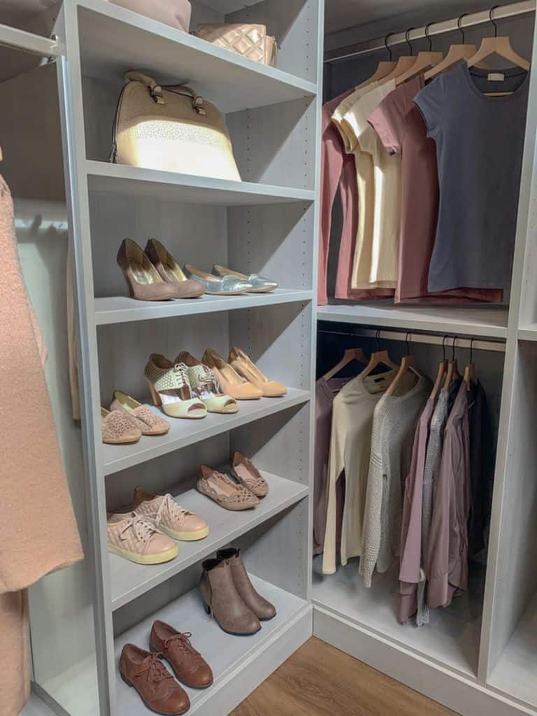 Closet with shelves of neatly arranged shoes, a handbag, and racks of folded and hanging clothes in soft neutral tones