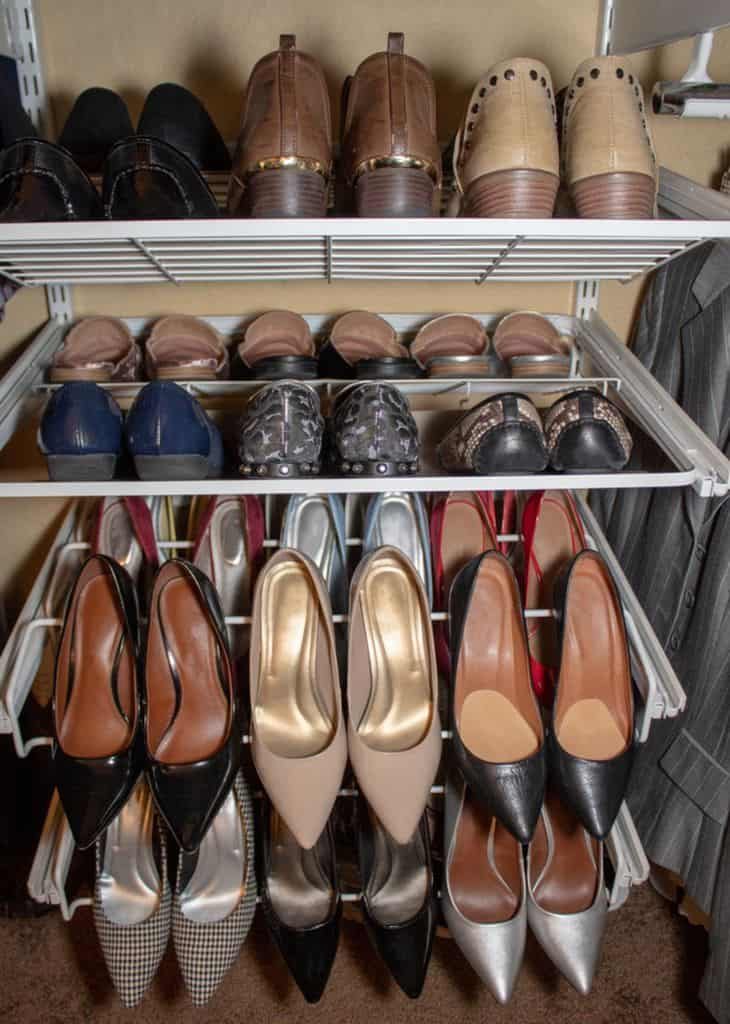 Shoe rack with various pairs of shoes: brown loafers, patterned flats, and high heels in black, beige, red, and silver tones