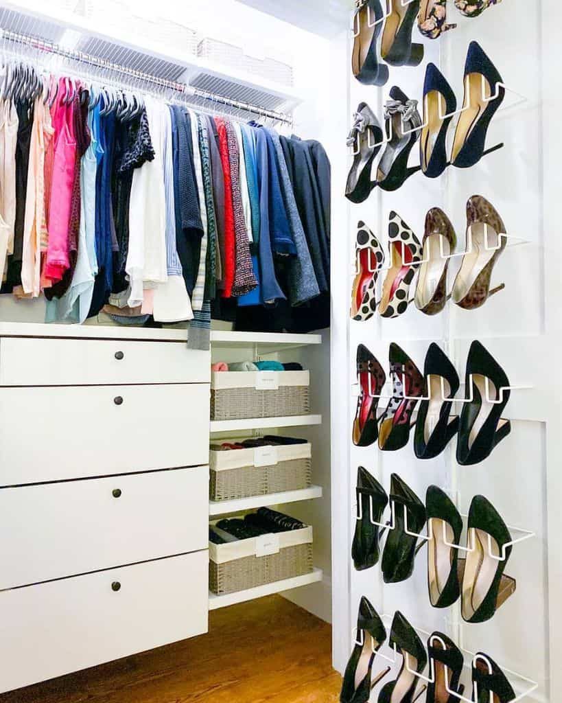 Organized closet with clothes on hangers, shoes displayed on the wall, and labeled baskets on shelves below hanging clothes