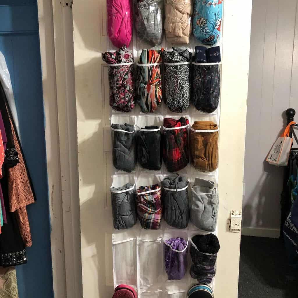 A wall-mounted shoe organizer being used to store various rolled-up fabrics and clothing items