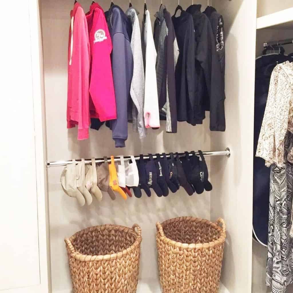 Organized closet with hoodies, shirts, and socks hanging, two woven baskets on the floor