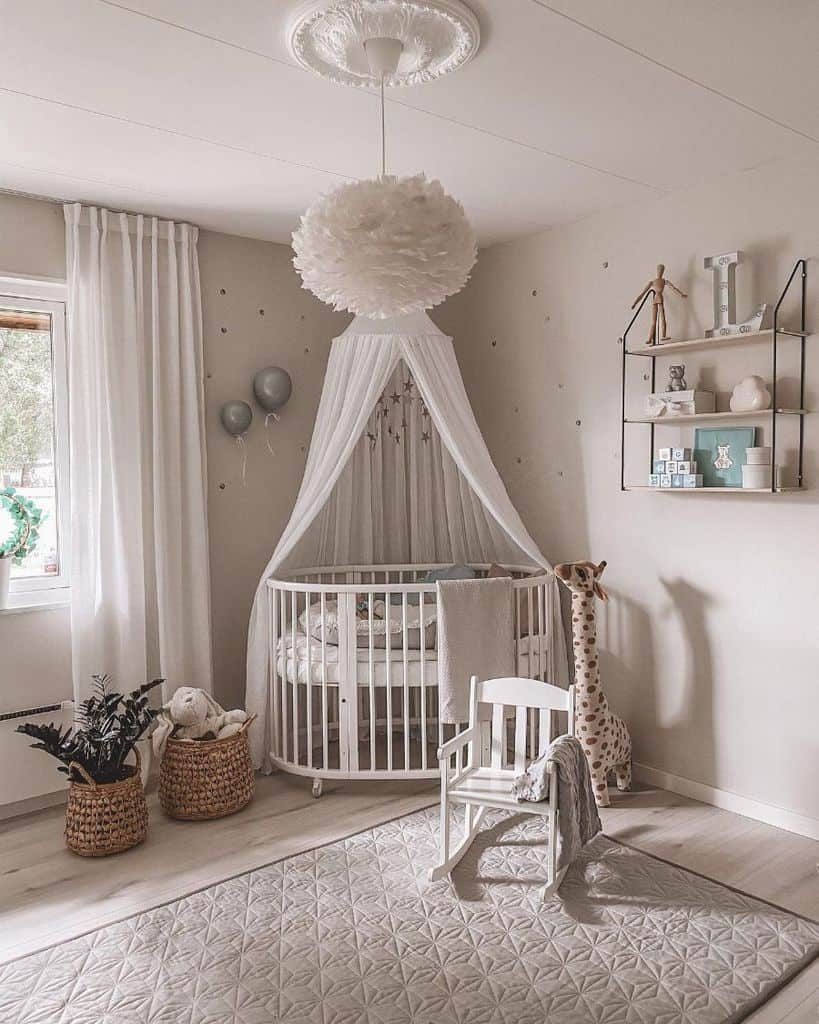 Elegant white nursery featuring a round crib with a sheer canopy, a plush feathered pendant light, a rocking chair, woven storage baskets, a giraffe plush toy, and a soft quilted rug, creating a cozy and serene atmosphere