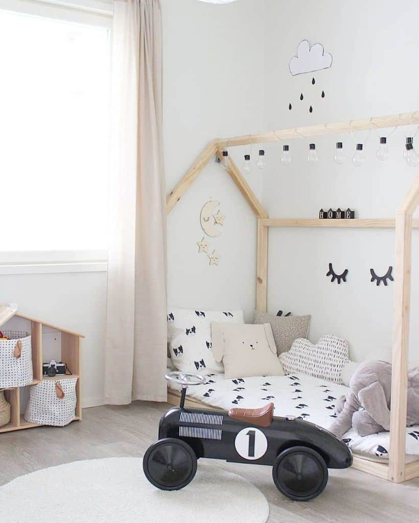 Minimalist kids' bedroom with a Scandinavian-inspired house-shaped wooden bed frame, cozy bedding with black-and-white prints, and soft plush pillows