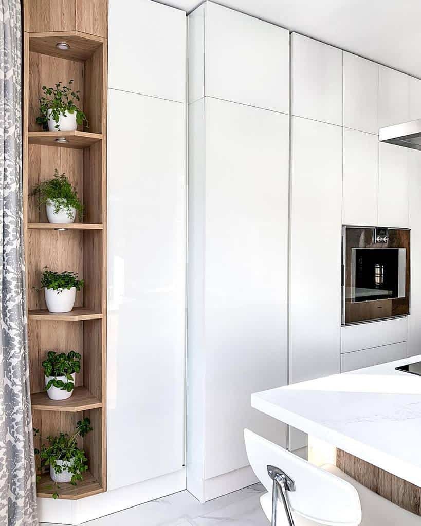 Modern kitchen with a built-in wooden shelf displaying potted herbs in white planters, blending greenery with sleek white cabinetry