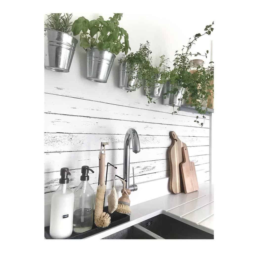 Farmhouse-style kitchen with a wall-mounted herb garden in metal pots, adding fresh greenery above a white shiplap backsplash