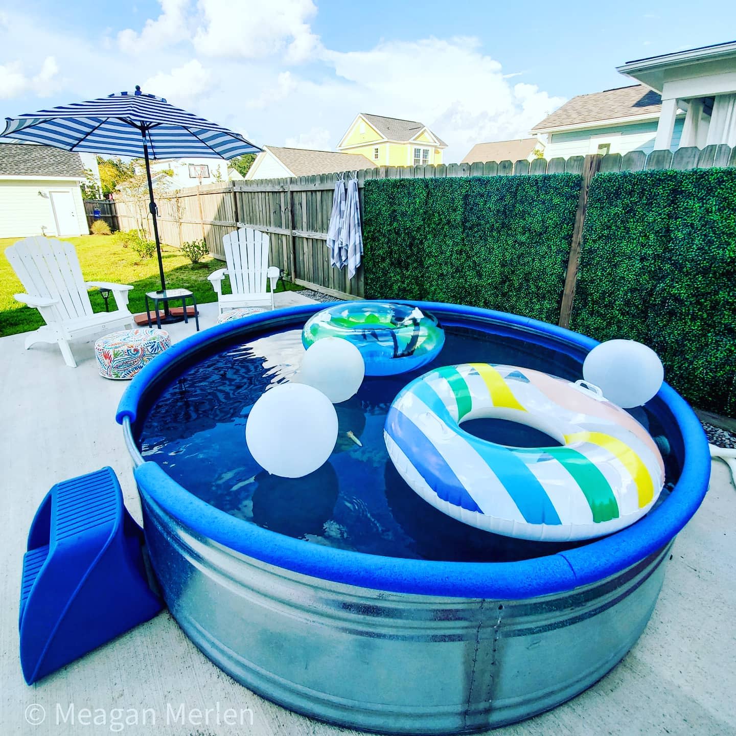 Round above-ground pool with three floats, surrounded by patio chairs and a striped umbrella, set on a concrete area