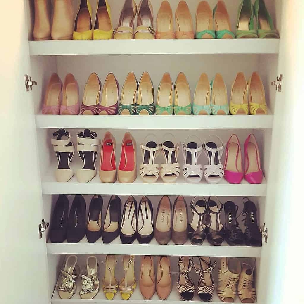 A neatly arranged collection of colorful high-heeled shoes on white shelves inside a closet