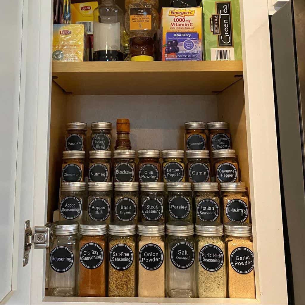 Organized spice cabinet with labeled jars containing a variety of seasonings, including paprika, cinnamon, cumin, and garlic powder