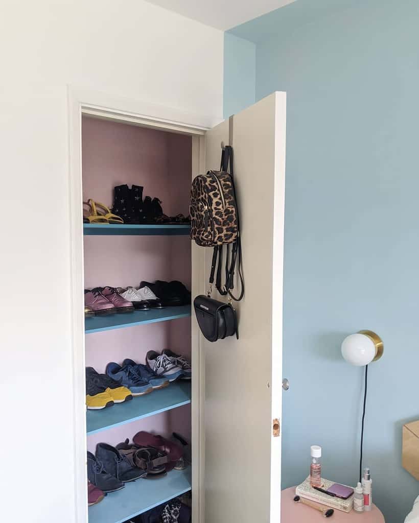 Open closet with shelves of shoes, a leopard print backpack, and a purse hanging on the door