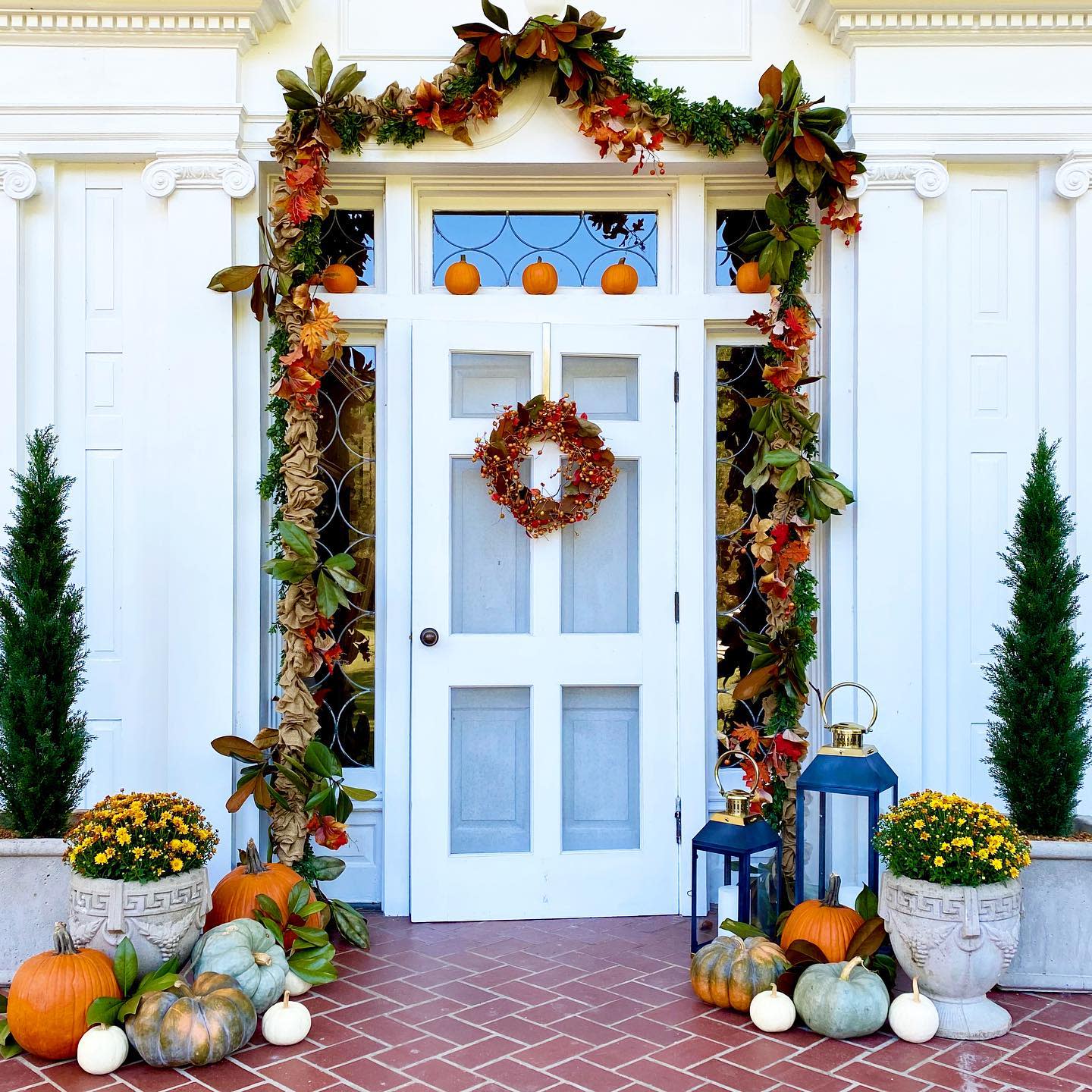 Festive autumn porch decorated with pumpkins, a wreath, and fall foliage garland