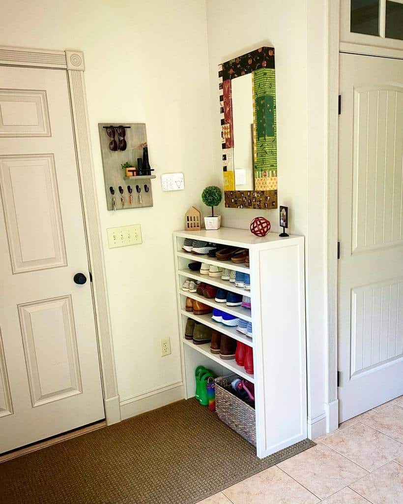 Compact white shoe rack with multiple shelves, neatly organizing footwear in an entryway with a mirror and key holder