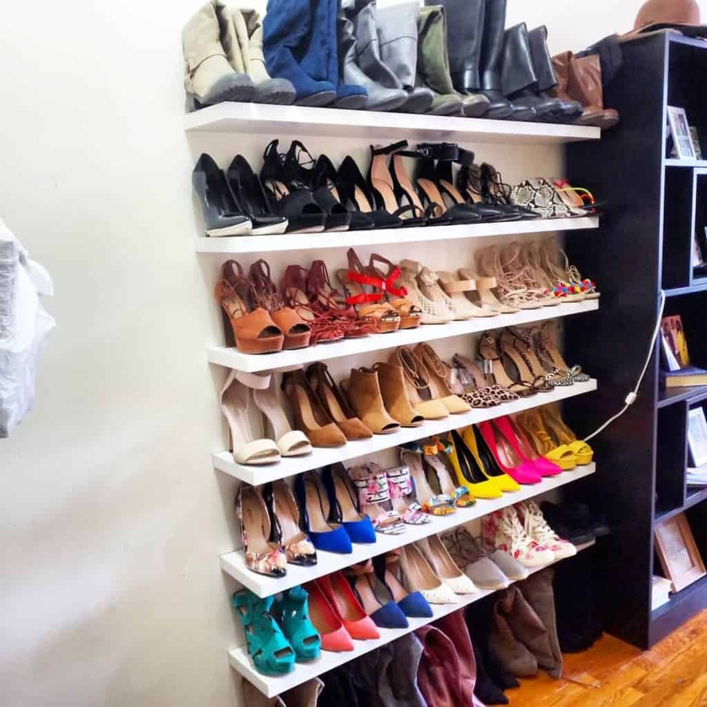 Shoe collection on shelves, organized by style and color, including boots, heels, and sandals, in a room corner