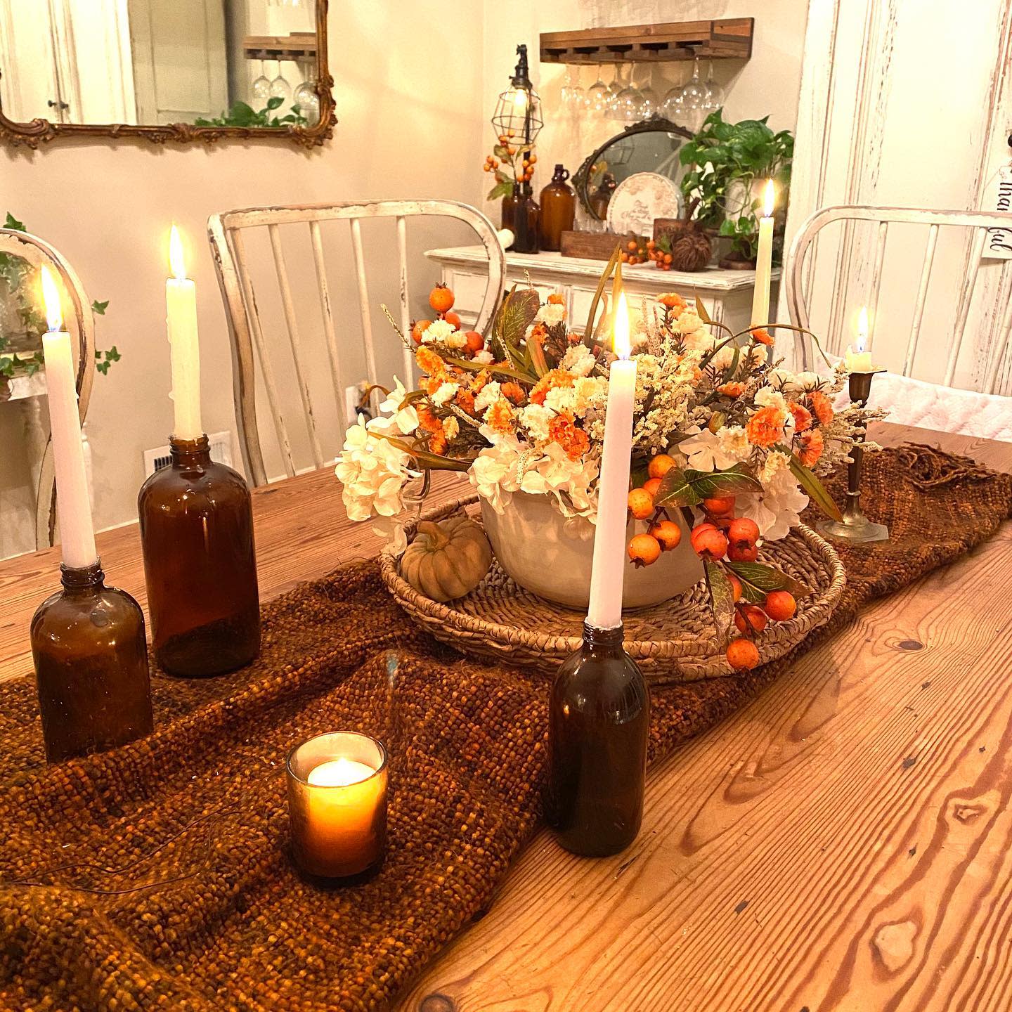 Cozy fall table setting with glowing candles, a floral centerpiece in warm hues, and rustic decor on a wooden table