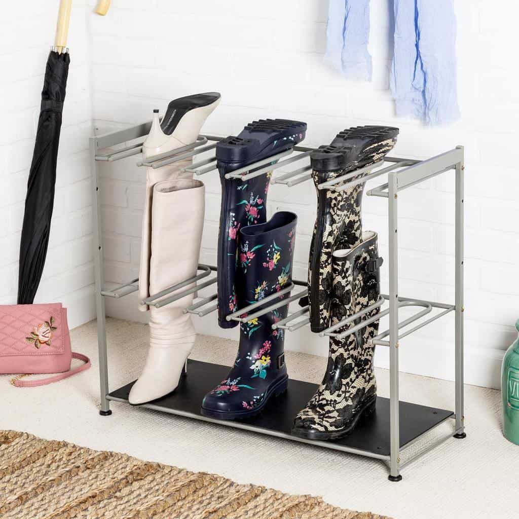 A metal boot rack holds various boots: white, black with flowers, and black with a pattern; nearby are an umbrella and a pink purse