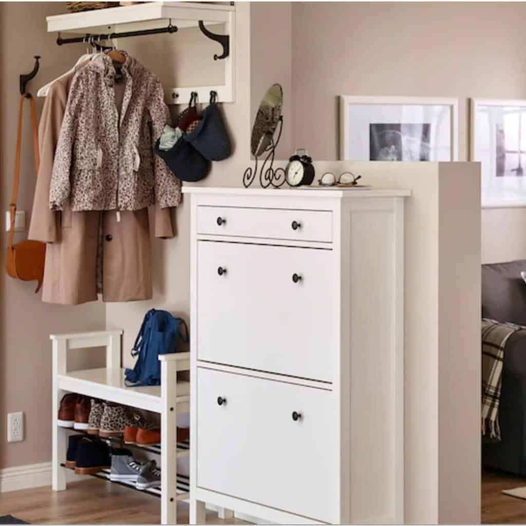 White shoe cabinet and storage bench in an entryway with coat hooks, shelves, and a cozy, organized space for shoes and accessories