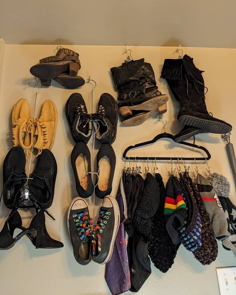 Shoes, hats, and scarves hanging on a wall, organized on hooks and hangers in a compact space